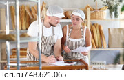 Man and woman sellers in bakery make calculations, work with paper documents and count using phone. Стоковое видео, видеограф Яков Филимонов / Фотобанк Лори