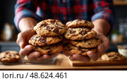 A person is holding a tray of chocolate chip cookies. Стоковое AI-изображение, AI-художник Ярославский Максим / Фотобанк Лори
