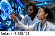 Two doctors are looking at a brain scan on a computer monitor. Стоковое AI-изображение, AI-художник Ярославский Максим / Фотобанк Лори