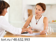 Woman listen attentively and intently to woman of seller, who tells about advantages of making microloan in credit institution. Стоковое фото, фотограф Яков Филимонов / Фотобанк Лори