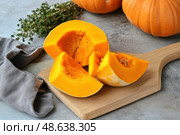 Cutting Fresh Pumpkins on Board. Baked pumpkin. Sliced raw Cucurbita maxima and spices for preparing soup, warm salad, fall dish. Thanksgiving food. Roasted vegetable in olive oil salt pepper, herbs. Стоковое AI-изображение, AI-художник Марина Демидюк / Фотобанк Лори