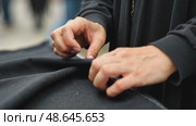 A close-up of a woman's hands sewing a black cloth banner, her fingers trembling slightly as she prepares for the Ashura process. Стоковое AI-видео, аниматор Sergey Grishin / Фотобанк Лори