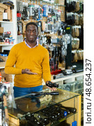 African american gunsmith demonstrating rifle scope for sale. Стоковое фото, фотограф Яков Филимонов / Фотобанк Лори