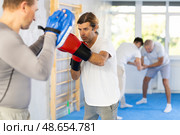 Man works out strength and speed of boxing punch mitts with help of partner in boxing paws. Стоковое фото, фотограф Яков Филимонов / Фотобанк Лори