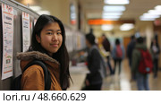 A student in casual attire stands in a bustling school hallway, glancing at information posters while peers move about. Стоковое AI-изображение, AI-художник Данила Большаков / Фотобанк Лори