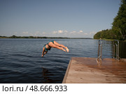 Fit woman diving headfirst from pier into lake. Healthy body, strong motion, natural summer activity. Стоковое фото, фотограф Скоробогатова Е. / Фотобанк Лори