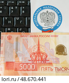 Письмо с эмблемой Федеральной налоговой службы, компьютерная клавиатура и российские деньги. Редакционное фото, фотограф Цибаев Алексей / Фотобанк Лори