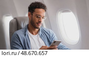 Young man using smartphone on airplane. Стоковое AI-видео, аниматор Юрий Поздников / Фотобанк Лори