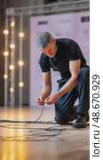 Stage technician connecting cables for event preparation. Стоковое AI-видео, аниматор Юрий Поздников / Фотобанк Лори