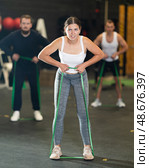 Sporty girl exercising with resistance band loop during group training. Стоковое фото, фотограф Яков Филимонов / Фотобанк Лори