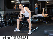 Man trains muscles of arms and back using dumb-bell shaped figure weighting. Стоковое фото, фотограф Яков Филимонов / Фотобанк Лори