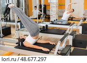 Girl performing reverse crunches with legs lift on Pilates reformer. Стоковое фото, фотограф Яков Филимонов / Фотобанк Лори