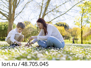 Mother and son building a small teepee with branches in a field of daisies. Стоковое фото, фотограф Константин Шишкин / Фотобанк Лори