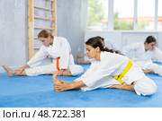 Group of teenage girls in white kimono do stretching before karate or judo training. Стоковое фото, фотограф Яков Филимонов / Фотобанк Лори