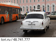The GAZ M21 Volga rear view. A white vintage-style Russian taxi. Редакционное фото, фотограф EugeneSergeev / Фотобанк Лори