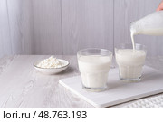 Pouring homemade kefir, buttermilk or yogurt with probiotics. Yogurt flowing from glass bottle. Стоковое фото, фотограф Наталия Попова / Фотобанк Лори