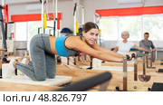 Girl performs exercise on reformer to improve coordination, balance, and posture. Стоковое фото, фотограф Яков Филимонов / Фотобанк Лори