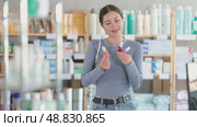 Positive young female customer choosing colorful nail polish in chemist's shop. Стоковое видео, видеограф Яков Филимонов / Фотобанк Лори