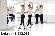 Group of enthusiastic smiling adult female and male ballet students focused on mastering graceful Demi rond de jambe par terre exercise at barre in mirrored well-lit choreography studio. Стоковое видео, видеограф Яков Филимонов / Фотобанк Лори