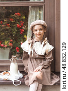 Vintage accessories and retro-style clothes. A small, beautiful girl with bows in her hair, in a beige dress and a beret outdoors with bagels and milk in a string bag. Стоковое фото, фотограф Photojuli / Фотобанк Лори