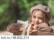 Vintage women's accessories and retro-style clothing. A small, beautiful girl with bows in her hair, in a beige dress and a beret outdoors. Стоковое фото, фотограф Photojuli / Фотобанк Лори