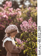 Vintage women's accessories and retro-style clothing. A small, beautiful girl with bows in her hair, in a beige dress and a beret outdoors. Стоковое фото, фотограф Photojuli / Фотобанк Лори