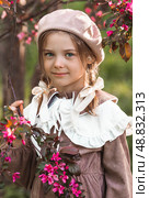 Vintage women's accessories and retro-style clothing. A small, beautiful girl with bows in her hair, in a beige dress and a beret outdoors. Стоковое фото, фотограф Photojuli / Фотобанк Лори