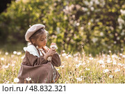 Vintage women's accessories and retro-style clothing. A small, beautiful girl with bows in her hair, in a beige dress and a beret outdoors. Стоковое фото, фотограф Photojuli / Фотобанк Лори