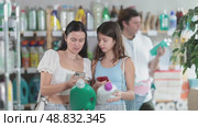 Focused woman with teen daughter scanning barcode on bottle of laundry detergent using phones to get product information in home care shop while father of family browsing shelves in background. Стоковое видео, видеограф Яков Филимонов / Фотобанк Лори