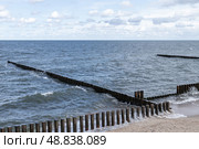 View of wooden breakwaters extending into the ocean, with gentle waves. Стоковое фото, фотограф EugeneSergeev / Фотобанк Лори