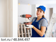 Woman builder using drill to bore hole in wall. Стоковое фото, фотограф Яков Филимонов / Фотобанк Лори