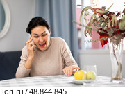 Asian woman swears at someone while talking on a mobile phone. Стоковое фото, фотограф Яков Филимонов / Фотобанк Лори
