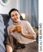 Portrait of an asian woman sitting on a sofa holding a mug. Стоковое фото, фотограф Яков Филимонов / Фотобанк Лори