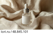 Skin care serum bottle on soft fabric background with natural elements. Флакон с сывороткой для ухода за кожей на фоне мягкой ткани с природными элементами. Стоковое AI-изображение, AI-художник Katsiaryna Repich / Фотобанк Лори