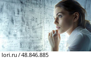 A young woman, wearing a white shirt, is intensely focused on a complex engineering diagram drawn on a whiteboard. The diagram is filled with intricate lines, shapes, and annotations. Стоковое AI-изображение, AI-художник Данила Большаков / Фотобанк Лори