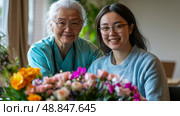 Intergenerational Portrait of an Asian Grandmother in Scrubs and a Granddaughter with Flowers, Celebrating Family Connection. Стоковое AI-изображение, AI-художник Данила Большаков / Фотобанк Лори