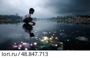 Child playing in polluted water beside a slum during cloudy weather in an urban area at dusk. Стоковое AI-изображение, AI-художник Сергей Толмачёв / Фотобанк Лори
