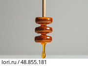 Honey Dripper With Golden Honey Droplet Against a Simple Background in a Kitchen Setting. Стоковое AI-изображение, AI-художник Юлия Гапеенко / Фотобанк Лори