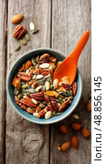 Healthy Nut and Seed Mix in a Bowl for Snacking on a Wooden Table. Стоковое AI-изображение, AI-художник Юлия Гапеенко / Фотобанк Лори