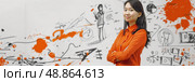 A young woman with dark hair stands in front of a whiteboard covered with sketches, scribbles, and orange paint splatters. Стоковое AI-изображение, AI-художник Данила Большаков / Фотобанк Лори