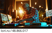 A man wearing a plaid shirt and a baseball cap sits in a dimly lit studio, mixing music on a digital audio workstation. Стоковое AI-изображение, AI-художник Данила Большаков / Фотобанк Лори