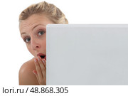 Surprised woman peering out from behind her laptop. Стоковое фото, агентство Ingram Publishing / Фотобанк Лори