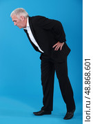 Man bending over to look at something on the floor. Стоковое фото, агентство Ingram Publishing / Фотобанк Лори