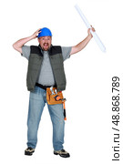 hilarious foreman standing against white background holding blueprints. Стоковое фото, агентство Ingram Publishing / Фотобанк Лори