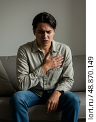 Young man suffering from acid reflux and heartburn on sofa. Стоковое AI-изображение, AI-художник Гайфуллина Дина / Фотобанк Лори
