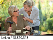 a young blonde woman touching shoulders of an old blonde woman taking a crutch in her hand. Стоковое фото, агентство Ingram Publishing / Фотобанк Лори