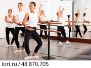 Active dancing women perform demi plie near the ballet barre, standing in a ballet stance. Стоковое фото, фотограф Яков Филимонов / Фотобанк Лори