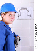 young woman wearing a blue jumpsuite in front of an electrical schema. Стоковое фото, агентство Ingram Publishing / Фотобанк Лори