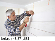 Grey-haired man replacing house paneling. Стоковое фото, агентство Ingram Publishing / Фотобанк Лори