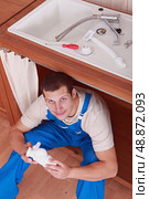 plumber under a sink is working. Стоковое фото, агентство Ingram Publishing / Фотобанк Лори